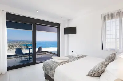 a bedroom with a bed and a balcony with a table at Regal Residence in Chania Town