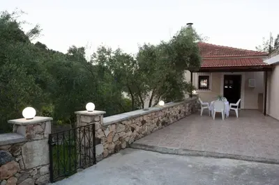 a house with a stone fence and a patio at Serenity Resort in Vrísai