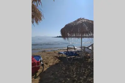 a beach with an umbrella and chairs and the ocean at Natasha's Luxury apartment by the sea in Galatás