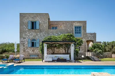 a villa with a swimming pool in front of a house at Beachfront villa Turquoise with private pool, BBQ and ping pong table in Chania Town