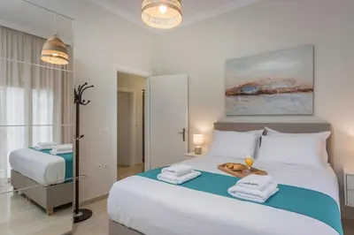 a white bedroom with two beds and a mirror at CALMERA Luxury Living in Chania Town