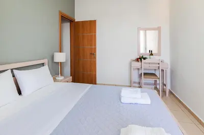 a white bedroom with a bed and a desk at Villa Krini in Kalathas