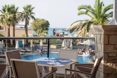 a table and chairs with a view of a swimming pool at Caldera Creta Paradise in Plataniás