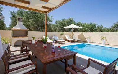 a patio with a table and chairs next to a swimming pool at Villa Elisabeth View in Plataniás