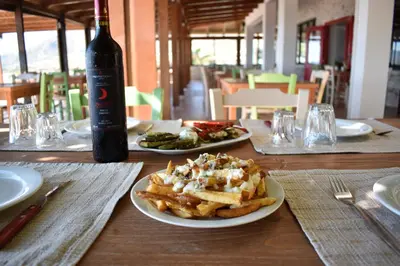 a table with two plates of food and a bottle of beer at Panorama Hotel in Falasarna