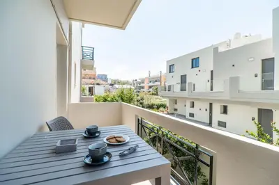 a table on a balcony with a view of a building at Rhoe Seaside Apartments in Agia Marina Nea Kydonias