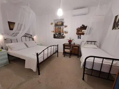 a bedroom with two beds with white sheets and a table at Olga's traditional stone house, Palaiochora in Kondokiníyion