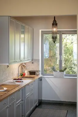 a kitchen with white cabinets and a window and a sink at The House By The Sea in Kato Daratso