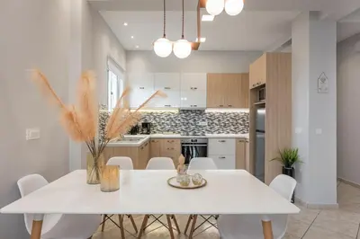 a white kitchen with a white table and chairs at JT Apartments in Kissamos