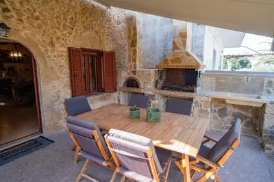 a dining room with a wooden table and a pizza oven at Villa Styliani in Kissamos