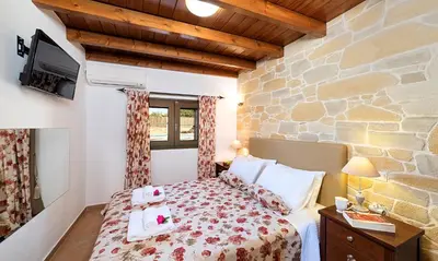 a bedroom with a bed and a stone wall at Cretan Kera Villa Heated Pool in Kerá