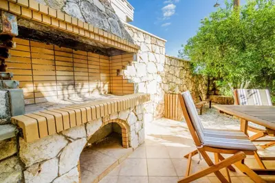 a stone wall with a table and a wooden bench at Andronikis House in Pithárion