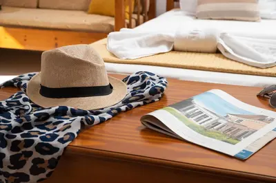 a hat and towels on a table with a book at Aphrodite Apartments in Kalyves