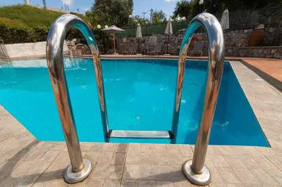a swimming pool with two metal hand rails next to it at Aphrodite Apartments in Kalyves