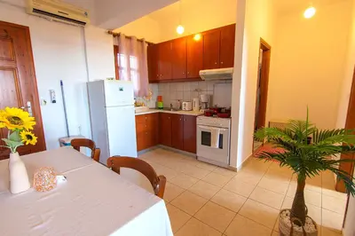 a kitchen with a table and a white refrigerator at Liviko Beach Apartments - only adults in Frangokastello