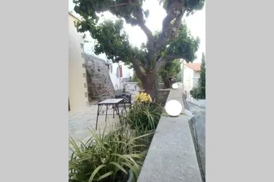 a garden with a tree and a table and chairs at Georgia's Village House in Kaláthenai