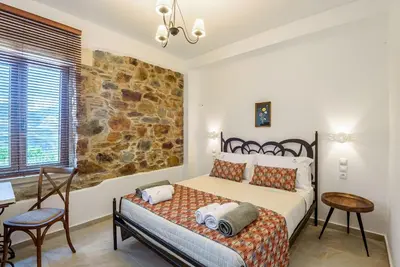 a bedroom with a bed and a stone wall at Minos Country Living Apartments in Agrilés
