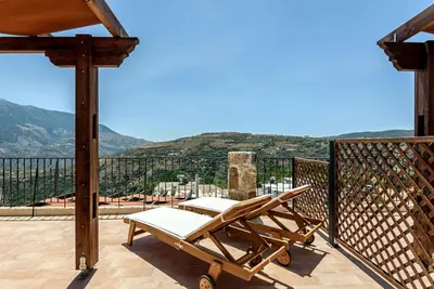 a chair on a balcony with a view at Minos Country Living Apartments in Agrilés
