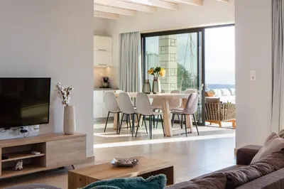 a living room with a couch and a table with chairs at Argyrie Villas, luxury, amazing sea view, heated pool in Kalleryianá