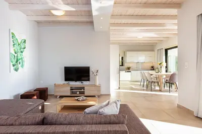 a living room with a couch and a tv at Argyrie Villas, luxury, amazing sea view, heated pool in Kalleryianá