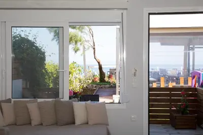 a living room with a couch and a sliding glass door at Litinakis Studios Sea View & Litinakis Studios Garden View 700 meters away in Agia Marina Nea Kydonias