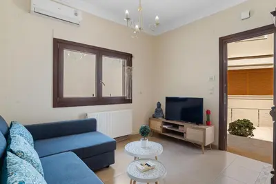a living room with a blue couch and a tv at Amphitrite Beach House in Chania Town