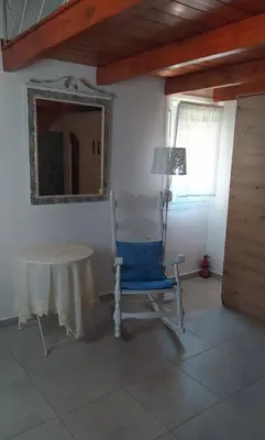 a room with a table and a blue chair and a mirror at House Gylisma in Kámbos