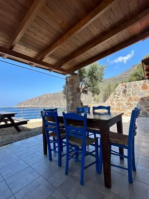 a wooden table and chairs on a patio with a view of the ocean at House Gylisma in Kámbos