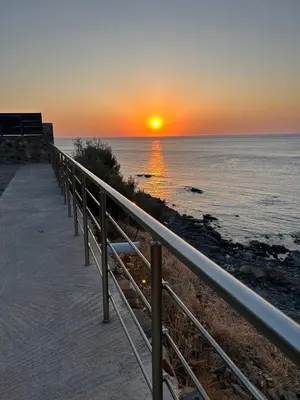 a sunset over the ocean with a metal railing at House Gylisma in Kámbos