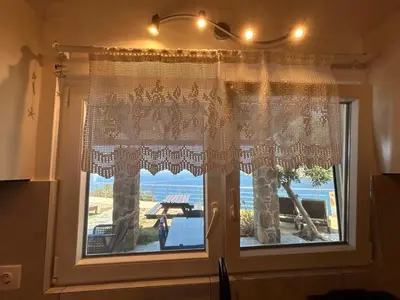 a window with a curtain and a view of the ocean at House Gylisma in Kámbos