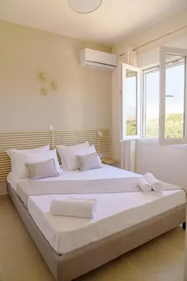 a white bedroom with a large bed with white pillows at RODOU Suites & Villas in Chania Town