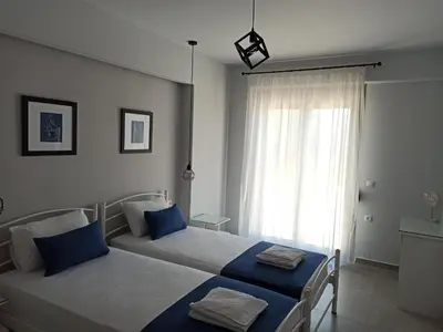 a bedroom with two beds with blue pillows and a window at Villa Dedalos in Kalamitsi Amygdali