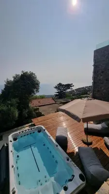 a hot tub on a patio with an umbrella at INO III Domus SWIMSPA by Amigdalokefali Elafonissi in AmigdhalokeFálion