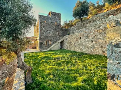an old stone wall with a green yard at INO III Domus SWIMSPA by Amigdalokefali Elafonissi in AmigdhalokeFálion