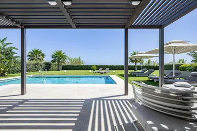 a swimming pool with chairs and an umbrella at Iniada Villas in Chania Town
