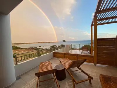 a rainbow over a balcony with chairs and a table at Houmas Apartments in Yialós