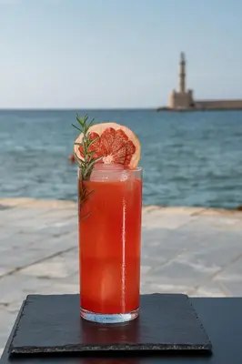 a drink sitting on a table next to the water at Anassa Chania Boutique Hotel in Chania Town