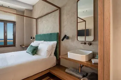 a bedroom with a bed and a sink and a mirror at Anassa Chania Boutique Hotel in Chania Town