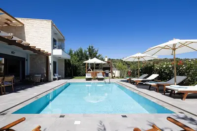 a swimming pool with patio furniture and umbrellas at Belair villas in Chania Town