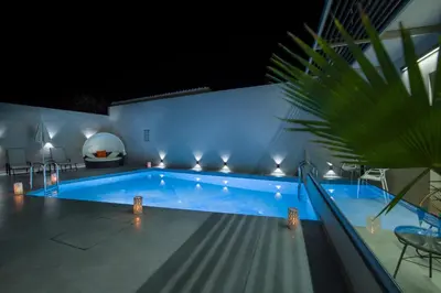 a swimming pool at night with lights on a house at xSuites - Adults Only Boutique Suites with Private Jacuzzi in Agia Marina Nea Kydonias