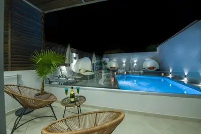 a patio with a swimming pool with chairs and a table at xSuites - Adults Only Boutique Suites with Private Jacuzzi in Agia Marina Nea Kydonias