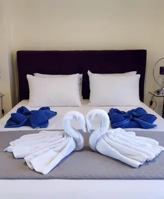 two swans laying on a bed with blue sheets at Villa Moma in Palio Gerani