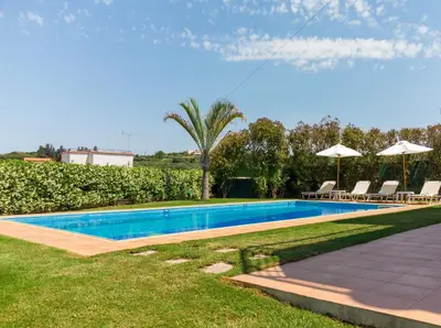 a swimming pool in a yard with chairs and umbrellas at Villa Moma in Palio Gerani
