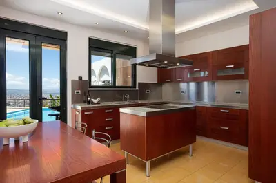 a kitchen with wooden cabinets and a table with a bowl of fruit at Villa City View - Heated Pool & Gym - Majestic views - 5 min drive from center in Chania Town