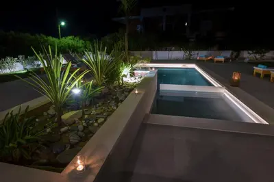 a swimming pool with lights in a yard at night at Eleanthi Modern Living in Galatás