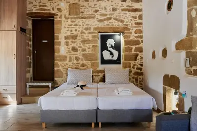 a bedroom with a bed and a stone wall at Studio Batilas in Kaláthenai