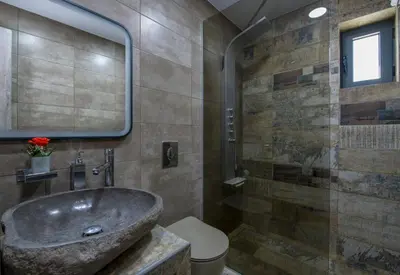 a bathroom with a stone sink and a shower at TWIN'S HOME LUXURY SUITES in Alikianós