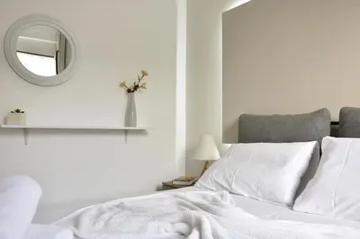 a white bedroom with a bed and a mirror at Casa de Campo 2 in Almirida