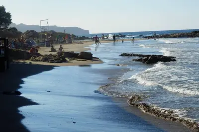 a beach with people walking on the sand and water at jenny's flat near the sea in Galatás