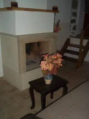 a fireplace with a vase of flowers on a table at Vafes Traditional Stone Houses in Vafés